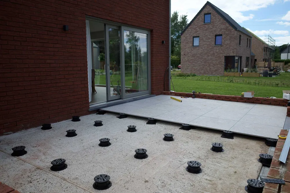 Plots Buzon PB posés sur la dalle, terrasse en cours devant une maison en brique